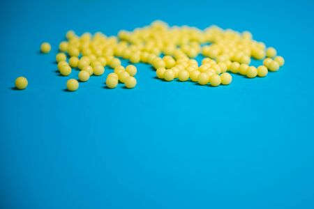 Yellow medical pills on blue background with copy space for text. Alternative homeopathy medicine, healthcare and wellness concept. Selective focusの写真素材