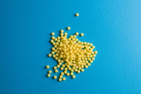 Yellow medical pills on blue background with copy space for text. Alternative homeopathy medicine,...