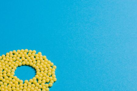 Yellow medical pills on blue background with copy space for text. Alternative homeopathy medicine, healthcare and wellness concept. Selective focusの写真素材