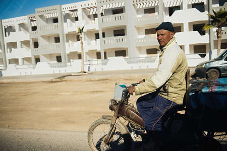 ESSAOUIRA, MOROCCO - JANUARY 17, 2020: Unidentified Moroccan man in dirty shirt rides a tricycle.のeditorial素材
