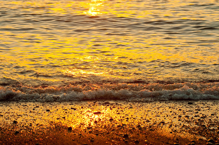 Sandy beach and waves turned orange at sunsetの写真素材