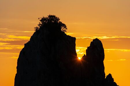 The rising sun from the other side of the rocky area of interesting shapeの写真素材