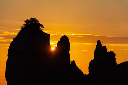 A rising sun rising from a crevice in an interesting shapeの写真素材