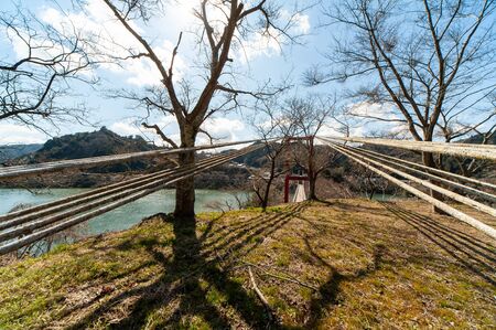 Mountain lake suspension bridge with blue sky and shadowの写真素材