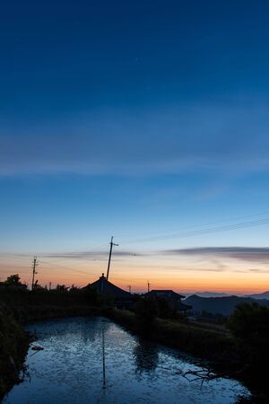 A sight with a sunrise sky and a pondの写真素材