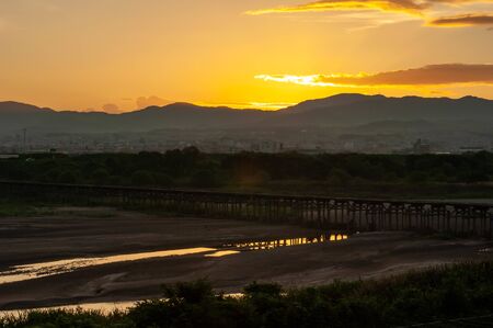 A wooden bridge over a river in Kyoto and the morning sunの写真素材