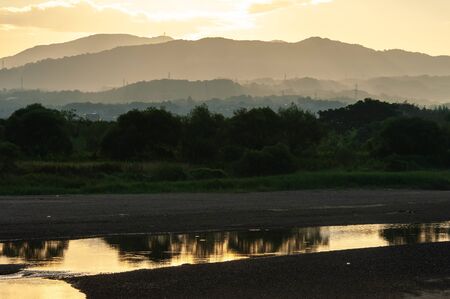 Mountains in the morning as seen from a wooden bridge over the river in Kyotoの写真素材