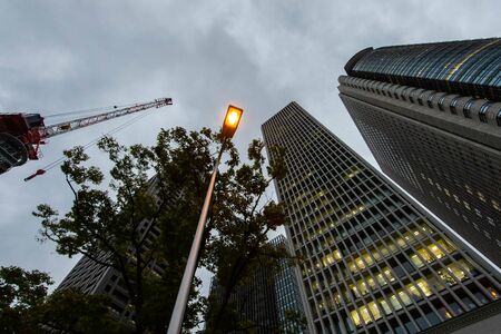 Cloudy skies, streetlights, cranes and buildings.の写真素材
