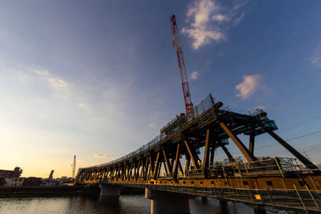 A steel bridge under construction, sunset and cloudsの写真素材