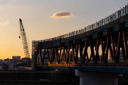 A steel bridge under construction, a crane and an interestingly shaped cloud