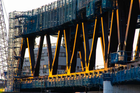 A railroad bridge under construction, turned orange by the setting sunの写真素材