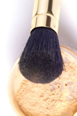powder brush in golden case with loose powder