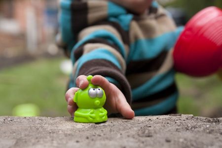 Close up of toddlers hand grabbing for a green plastic alienの写真素材