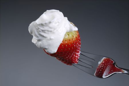 Strawberry on a fork with creamの写真素材