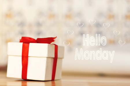 hello monday message with white gift box with red ribbon on wood backgroundの写真素材