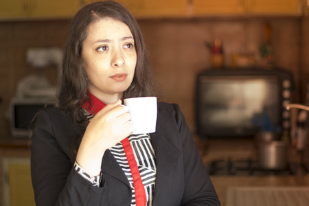 beautiful muslim young business woman hold cup of coffee in kitchen and dreamingの写真素材