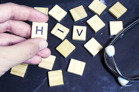 hand woman hold a wood letter h HIV ( Human Immunodeficiency Virus) letters and stethoscope on wood backgroundの写真素材