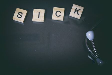 wooden cube letter sick and stethoscope on reflection backgroundの写真素材