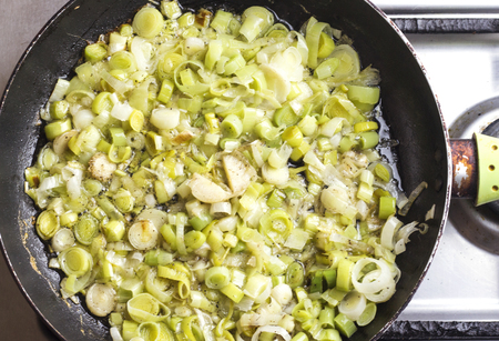 Fresh green leek sautÃ©ing in rusty pan on stoveの写真素材