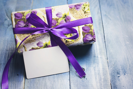 gift box with purple ribbon and floral paper and white card for events