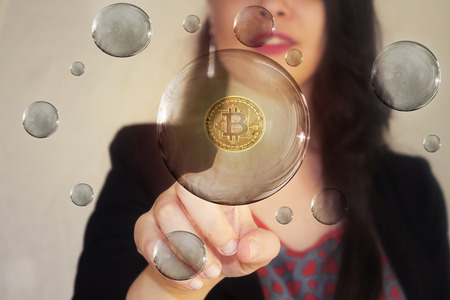 Portrait of a beautiful young woman pointing her finger to bitcoin in transparent bubble