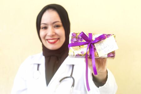 happy muslim woman giving a purple gift box with happy valentine's day cardの写真素材