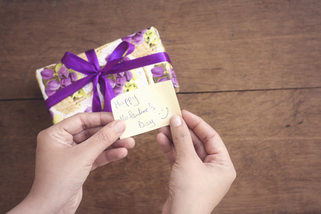 gift box with purple ribbon and floral paper with hand holding  happy valentine's day cardの写真素材