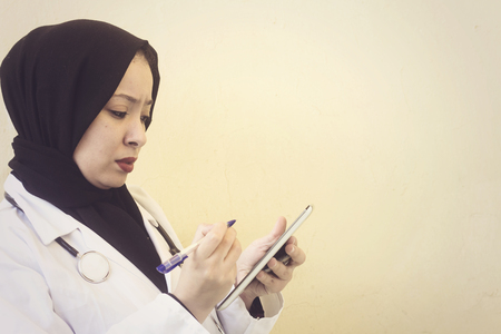 beautiful muslim woman holding tablet and pen at workの写真素材