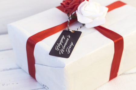 white gift with beautiful red and white flower and tag with happy women's dayの写真素材