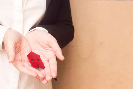 real estate agent female hand holding a small red house, sell house business conceptの写真素材
