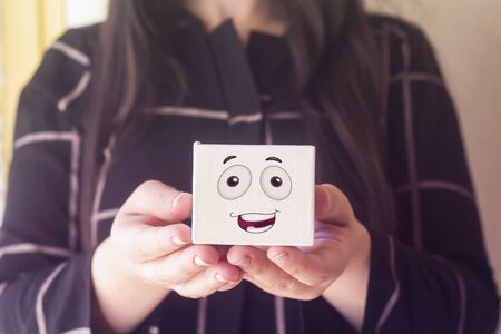 woman with beautiful hair holding white box with happy face emoticonの写真素材