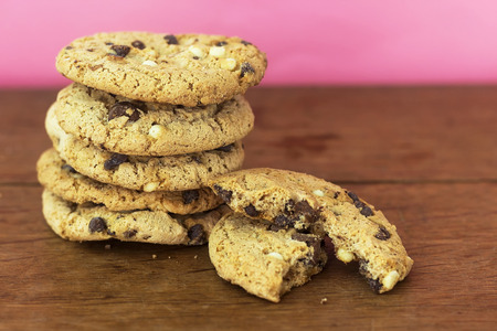 homemade white and black chocolate cookies on wood table with pink background