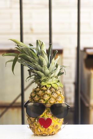 fresh pineapple fruit wearing sunglasses on woodenの写真素材