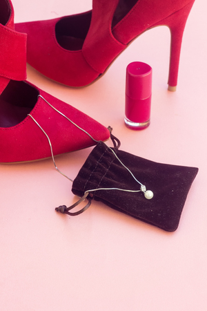 beautiful pump hight heeled and pink nail polish bottle and white pearl necklaceの写真素材