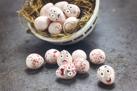 Delicious pink chocolate Easter eggs with funny cartoon face on nest, happy Easter eggs concept