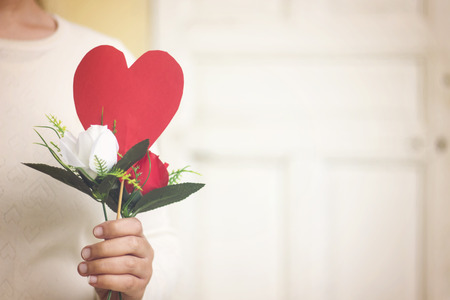 woman hand holding red paper heart shape and flowers for valentine's dayの写真素材