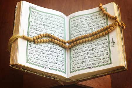 rosary and holy quran book on wood standの写真素材