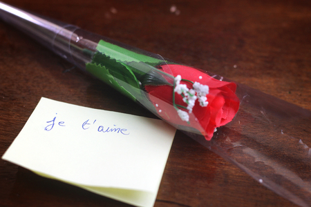 i love you translated in french written on yellow card with red flowerの写真素材