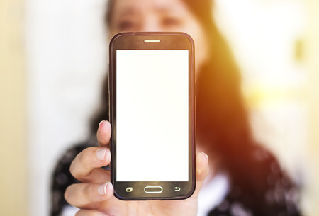 arabic woman wearing arabic dress and holding mobile phone and showing it to cameraの写真素材