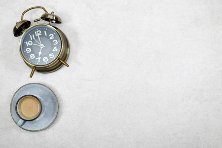 alarm o'clock showing 7 o'clock with cup of milk coffee on gray grunge background