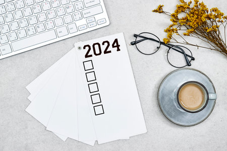 New year goals 2024 on desk. 2024 goals list with notebook, coffee cup, gypsophila, keyboard, eye glasses. Resolutions, plan, goals, action, checklist, idea concept. New Year 2024の写真素材