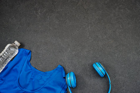 Healthy lifestyle, sport or athlete's equipment set : female clothing and bottle of water with blue wireless headphone on gray backgroundの写真素材