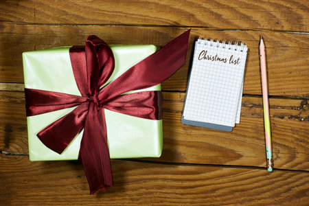 gift box with christmas list notebook on wood table
