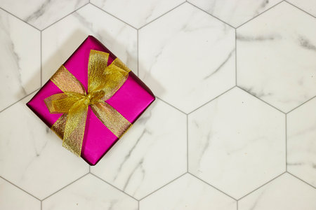 pink gift box with golden ribbon on hexagon backgroundの写真素材