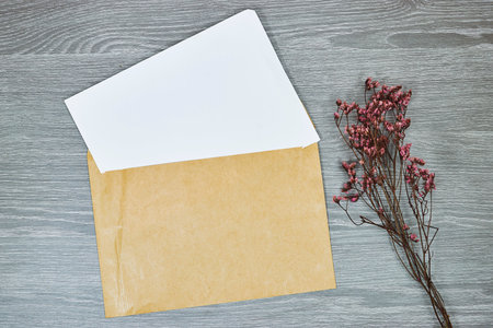 White envelope mock-up, blank template with yellow gypsophila flower on wooden gray tableの写真素材