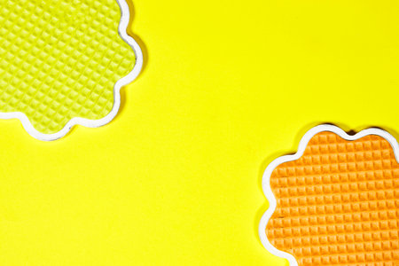 colorful waffles shape saucer on yellow background with copy spaceの写真素材