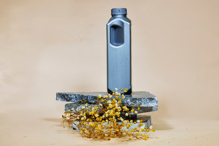 gray plastic bottle or canister on marble podium or stone with yellow gypsophilaの写真素材