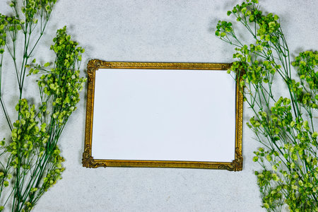 golden picture or photo frame mockup with green baby's breath, gypsophila on gray grunge backgroundの写真素材