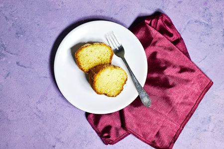 slice of delicious coconut bundt cake in white plate isolated on purple background