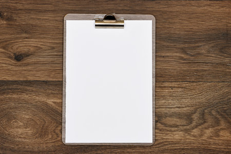 Classic metal clipboard with blank white paper on wood table
